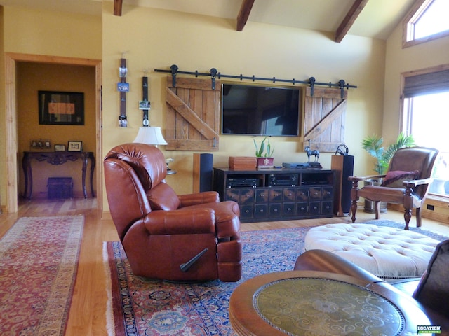 living area featuring lofted ceiling with beams, a barn door, and wood finished floors