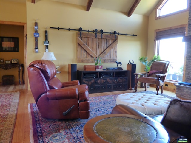 living area featuring a barn door, high vaulted ceiling, beam ceiling, and wood finished floors