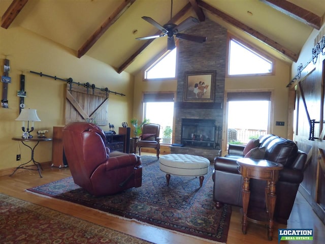 living area with a wealth of natural light, wood finished floors, and a barn door