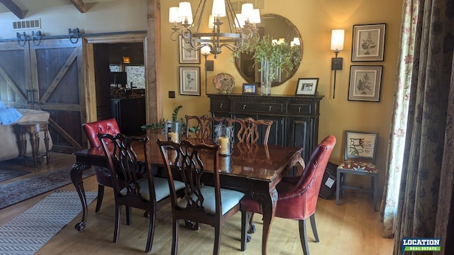 dining area with a chandelier, wood finished floors, visible vents, and a barn door