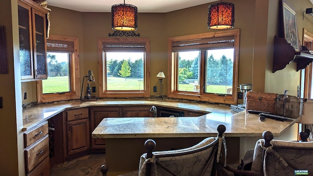 kitchen with light stone counters, decorative light fixtures, a peninsula, a kitchen bar, and glass insert cabinets