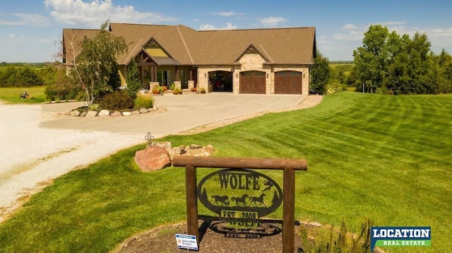 view of front of property featuring a garage, driveway, a front lawn, and stone siding