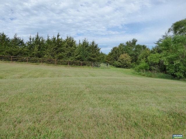 view of yard with fence and a rural view