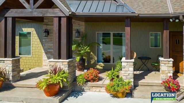 entrance to property featuring stone siding, metal roof, roof with shingles, a standing seam roof, and a porch