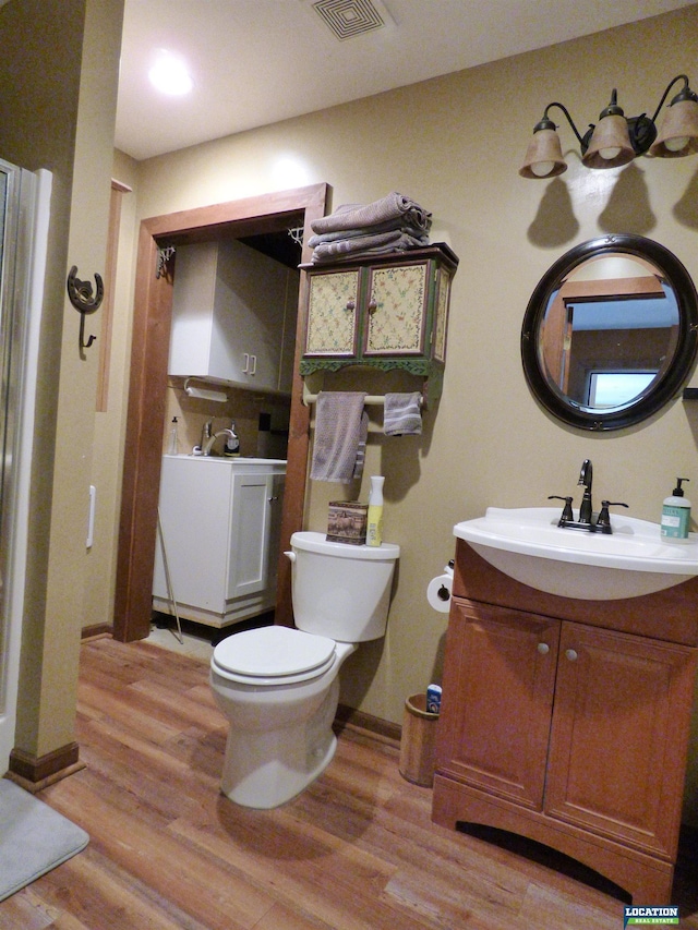 bathroom featuring visible vents, vanity, toilet, and wood finished floors