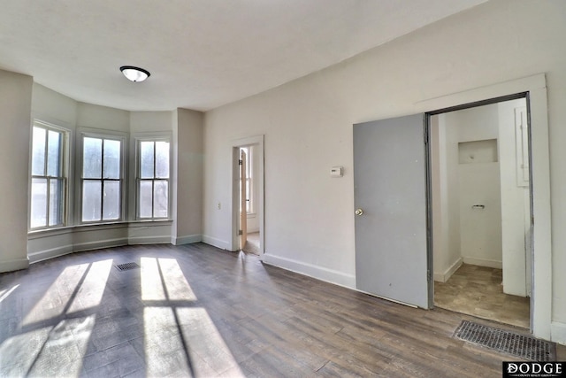 unfurnished room featuring visible vents, baseboards, and wood finished floors