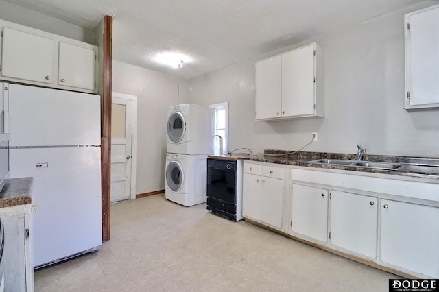 washroom with a textured ceiling, laundry area, a sink, light floors, and stacked washer and clothes dryer