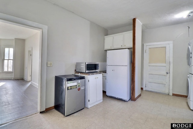 kitchen with refrigerator, white cabinets, baseboards, freestanding refrigerator, and stainless steel microwave