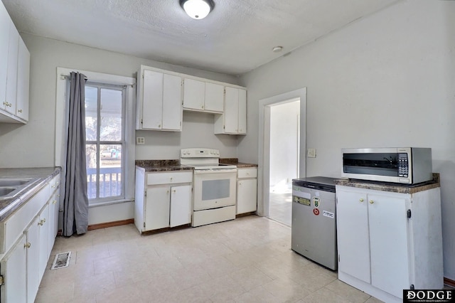 kitchen featuring white electric stove, visible vents, white cabinets, fridge, and stainless steel microwave