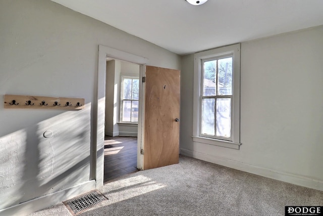 carpeted foyer with baseboards and visible vents