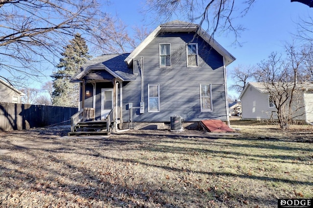 rear view of property featuring a shingled roof and fence