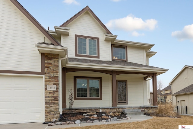 view of front of home featuring covered porch, stone siding, and an attached garage