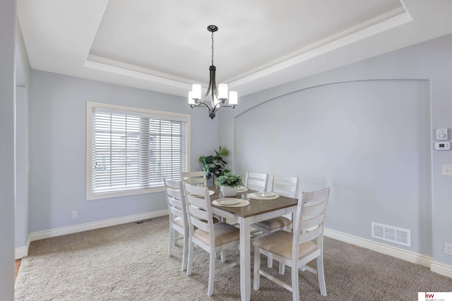 dining room featuring light carpet, a raised ceiling, visible vents, and baseboards