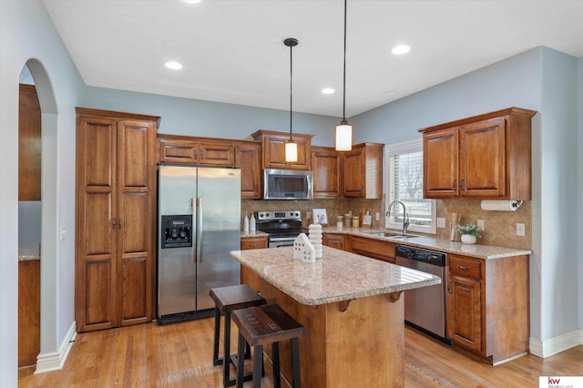 kitchen featuring stainless steel appliances, tasteful backsplash, a sink, and brown cabinets