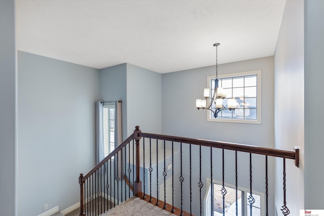 staircase with a chandelier, carpet, and baseboards