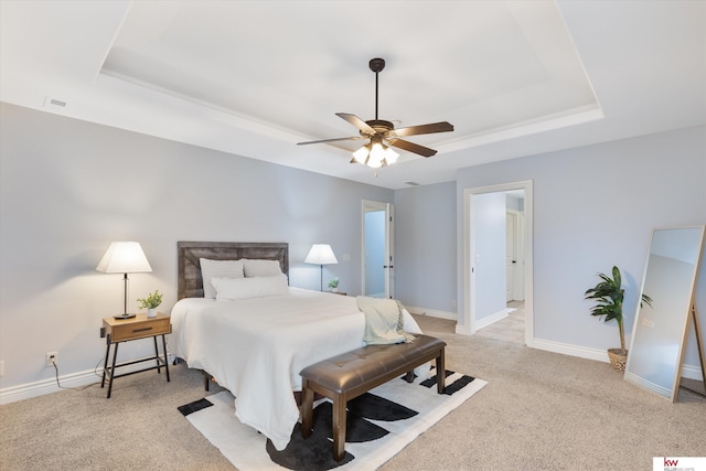 bedroom with light carpet, a raised ceiling, a ceiling fan, and baseboards