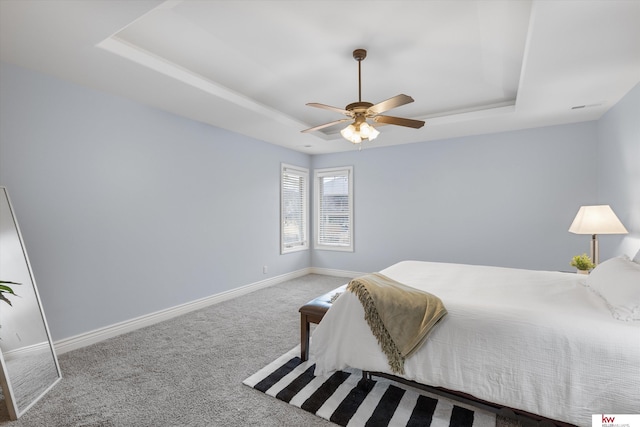 bedroom with a tray ceiling, carpet, a ceiling fan, and baseboards