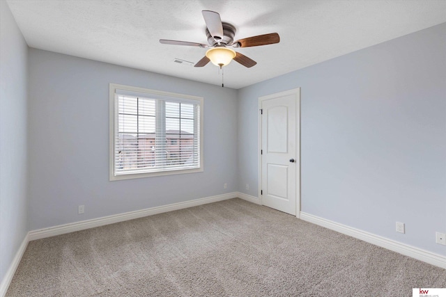 carpeted spare room featuring visible vents, baseboards, ceiling fan, and a textured ceiling