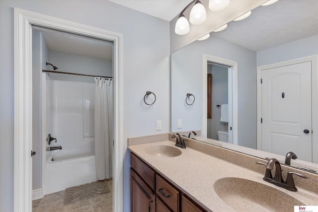 full bathroom featuring shower / bath combo, a sink, a textured ceiling, and double vanity