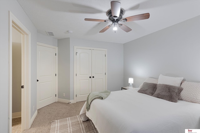 bedroom with a closet, light colored carpet, visible vents, ceiling fan, and baseboards