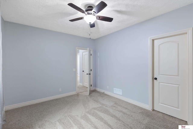 empty room with baseboards, visible vents, a ceiling fan, a textured ceiling, and carpet flooring