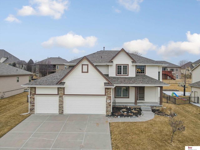 view of front of home featuring a porch, concrete driveway, fence, stone siding, and a front lawn