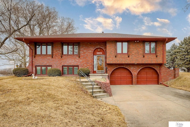 split foyer home with concrete driveway, brick siding, and an attached garage