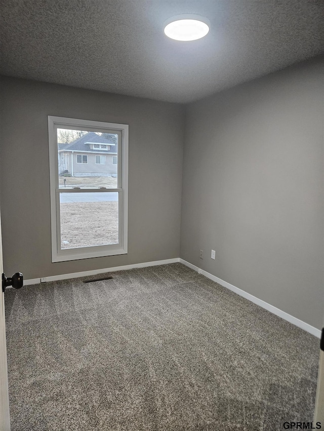 carpeted empty room featuring a textured ceiling, visible vents, and baseboards