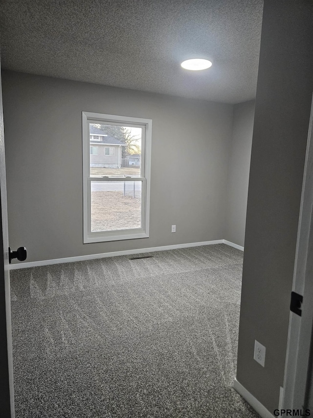 spare room with a textured ceiling, carpet, visible vents, and baseboards