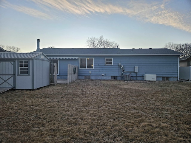 rear view of house with central air condition unit, a shed, an outbuilding, and a yard