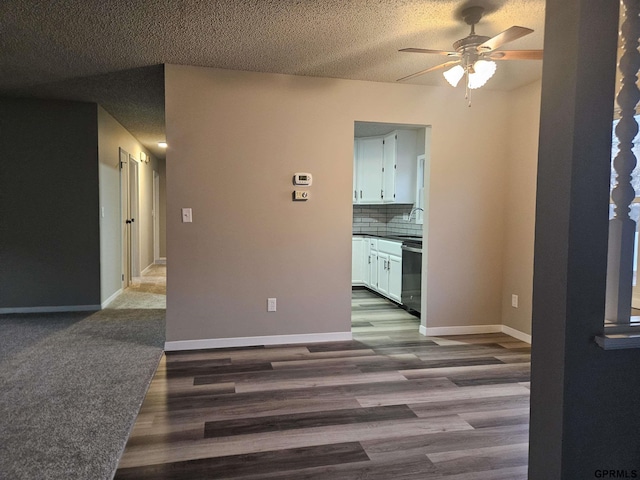 unfurnished room with a textured ceiling, ceiling fan, dark wood-type flooring, a sink, and baseboards