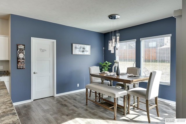 dining room featuring a notable chandelier, baseboards, and wood finished floors