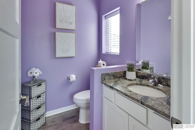 bathroom with baseboards, toilet, wood finished floors, and vanity