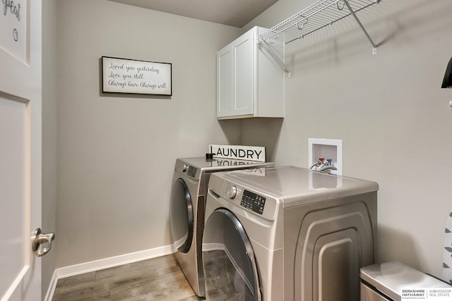 washroom with baseboards, cabinet space, wood finished floors, and washing machine and clothes dryer