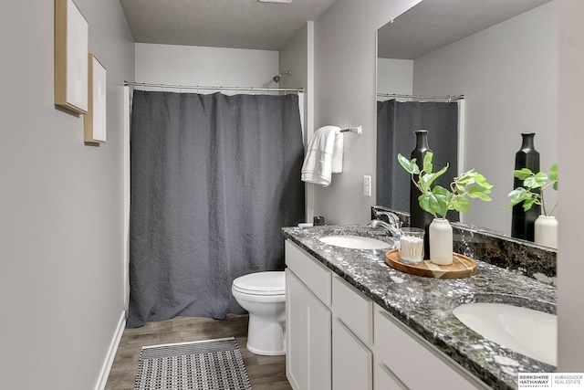 full bath with double vanity, toilet, wood finished floors, and a sink