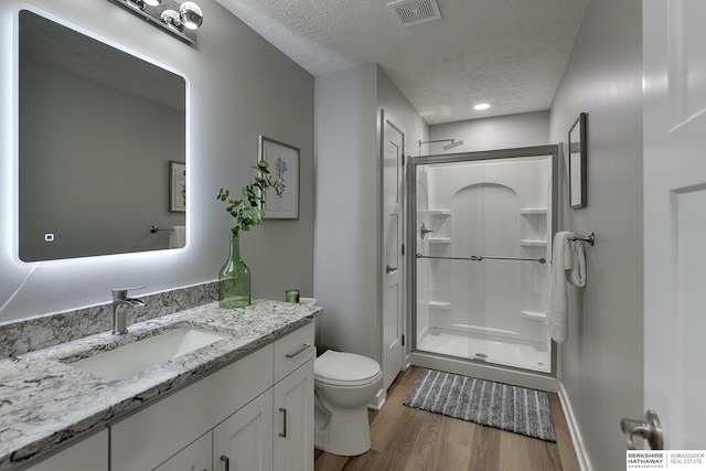 full bath featuring visible vents, a stall shower, toilet, and a textured ceiling