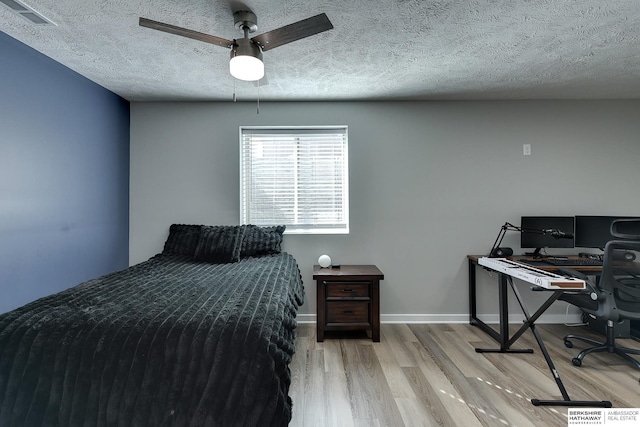 bedroom featuring visible vents, a textured ceiling, baseboards, and wood finished floors