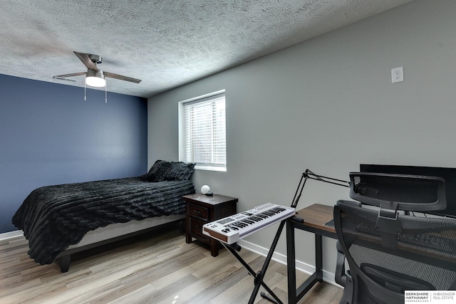 bedroom featuring baseboards, ceiling fan, a textured ceiling, and light wood-style floors