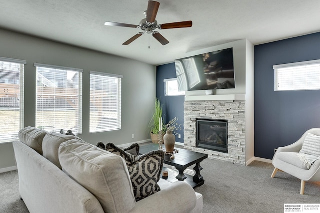 living room with carpet flooring, ceiling fan, a fireplace, and baseboards