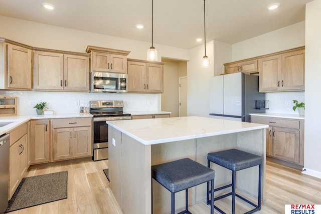 kitchen with light wood finished floors, a center island, decorative backsplash, a kitchen breakfast bar, and stainless steel appliances