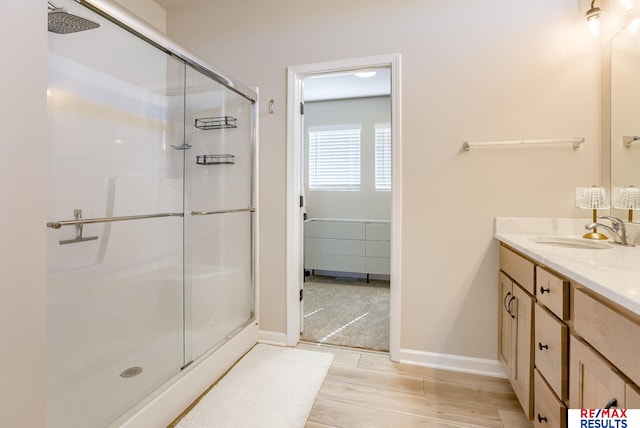 full bathroom with baseboards, vanity, and a shower stall