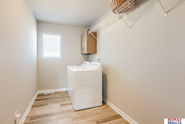 washroom with baseboards, cabinet space, light wood-style floors, and washer and clothes dryer