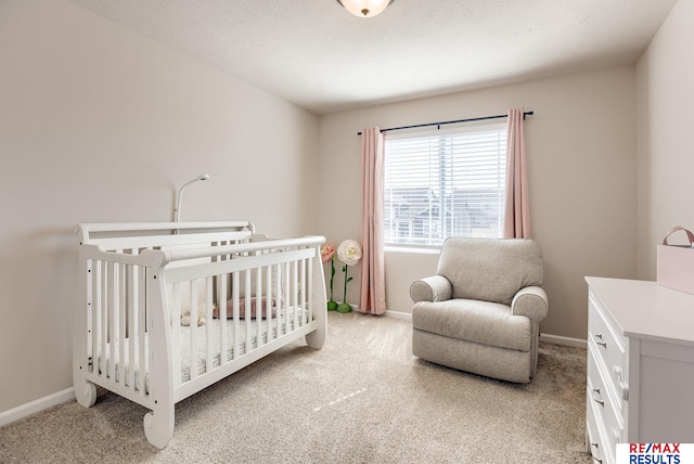 bedroom featuring baseboards, light carpet, a nursery area, and a textured ceiling