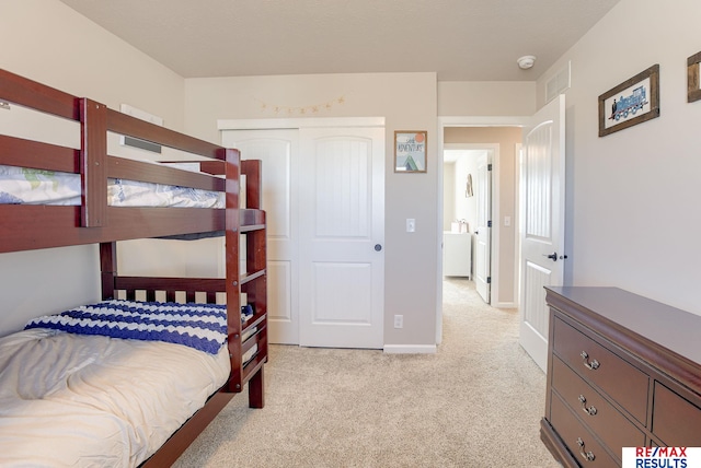 bedroom with light colored carpet, visible vents, a closet, and baseboards