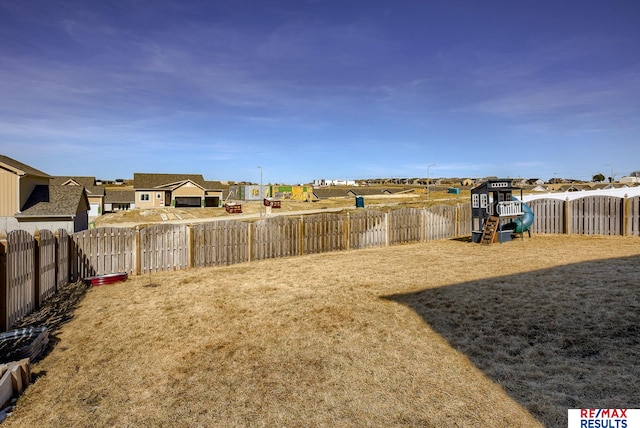 view of yard featuring a residential view, a fenced backyard, and a playground