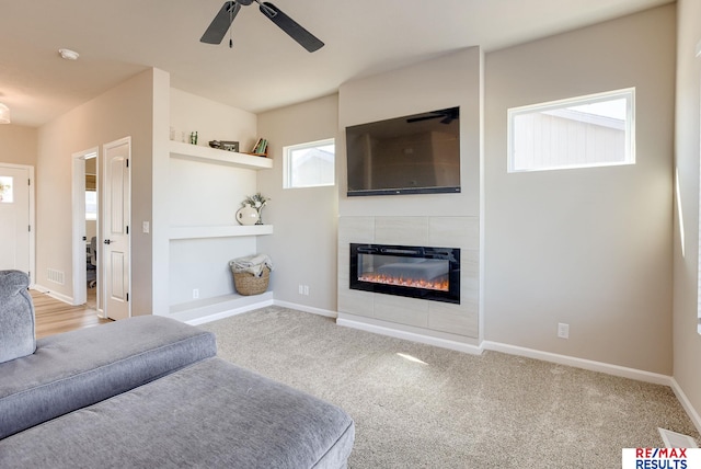 carpeted living area featuring a fireplace, baseboards, and ceiling fan