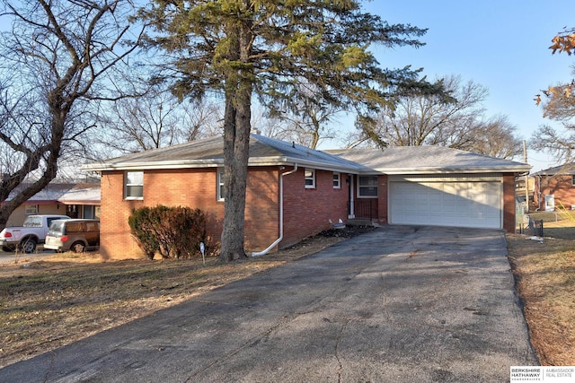 ranch-style home with a garage, aphalt driveway, and brick siding