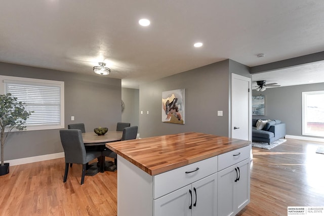 kitchen with white cabinets, light wood-type flooring, baseboards, and wooden counters