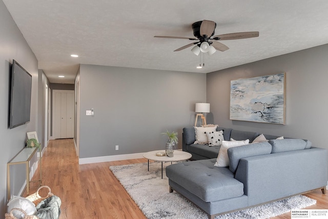 living room featuring baseboards, light wood-style flooring, ceiling fan, a textured ceiling, and recessed lighting