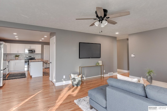 living room featuring ceiling fan, light wood-style flooring, recessed lighting, visible vents, and baseboards